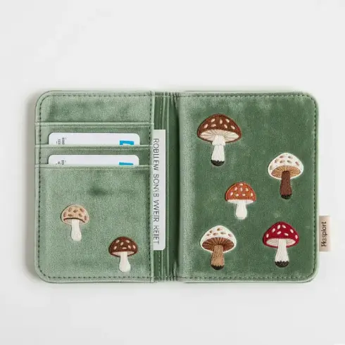 

A sage green velvet passport cover with hand-stitched mushroom motifs in earthy tones.