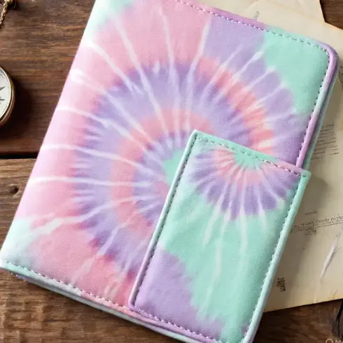 A soft pastel tie-dye passport cover (pink, lavender, mint) in eco-friendly canvas.