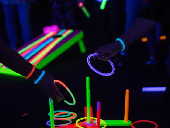  Guests tossing glow stick rings at neon-painted stakes