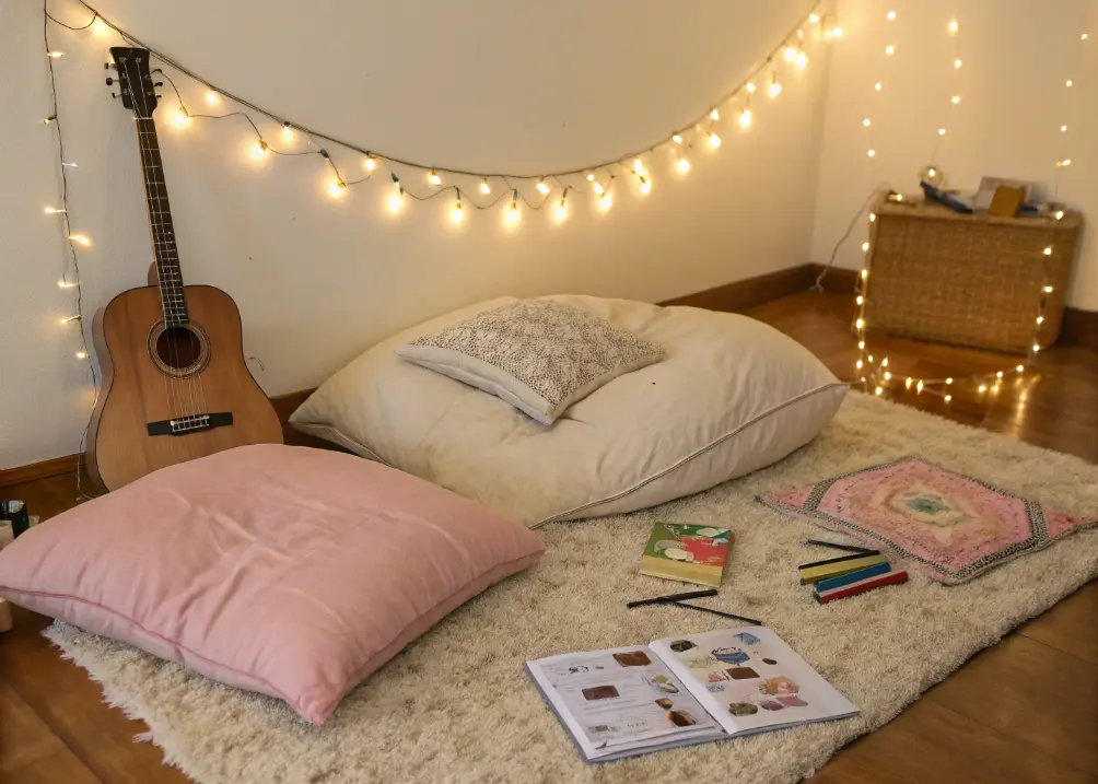 a floor cushion setup with rugs and fairy lights