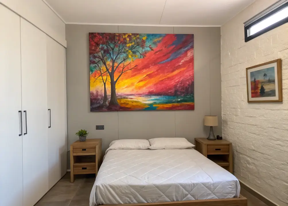  A large, colorful abstract painting above the bed in a small room, with minimal other decor to let the art steal the show.
