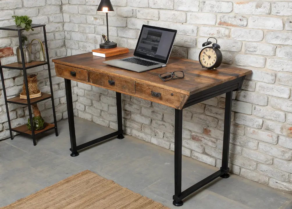 A desk with a vintage brass clock next to a leather journal and a small cactus, set against a dark wood wall.