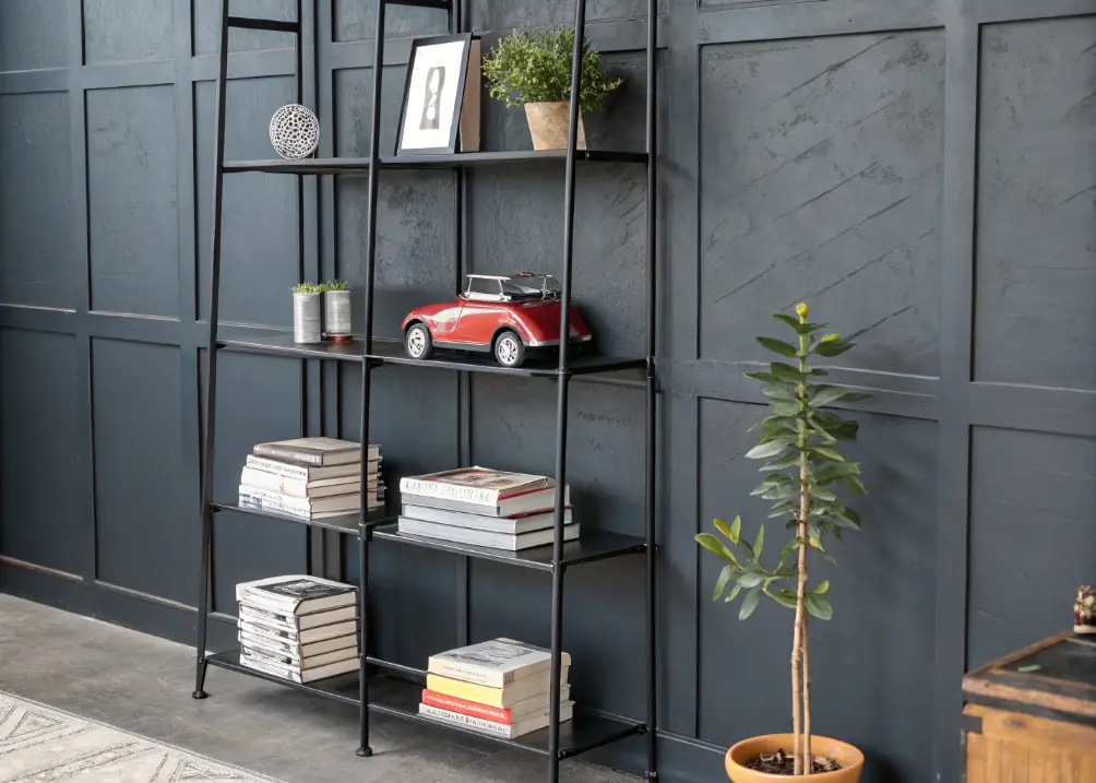 Black metal shelves holding books, a model car, and a small plant, against a dark gray wall.