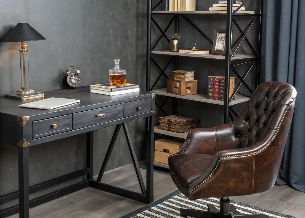 A sleek black desk with a leather chair, industrial shelves holding a whiskey decanter and books, against a charcoal accent wall.